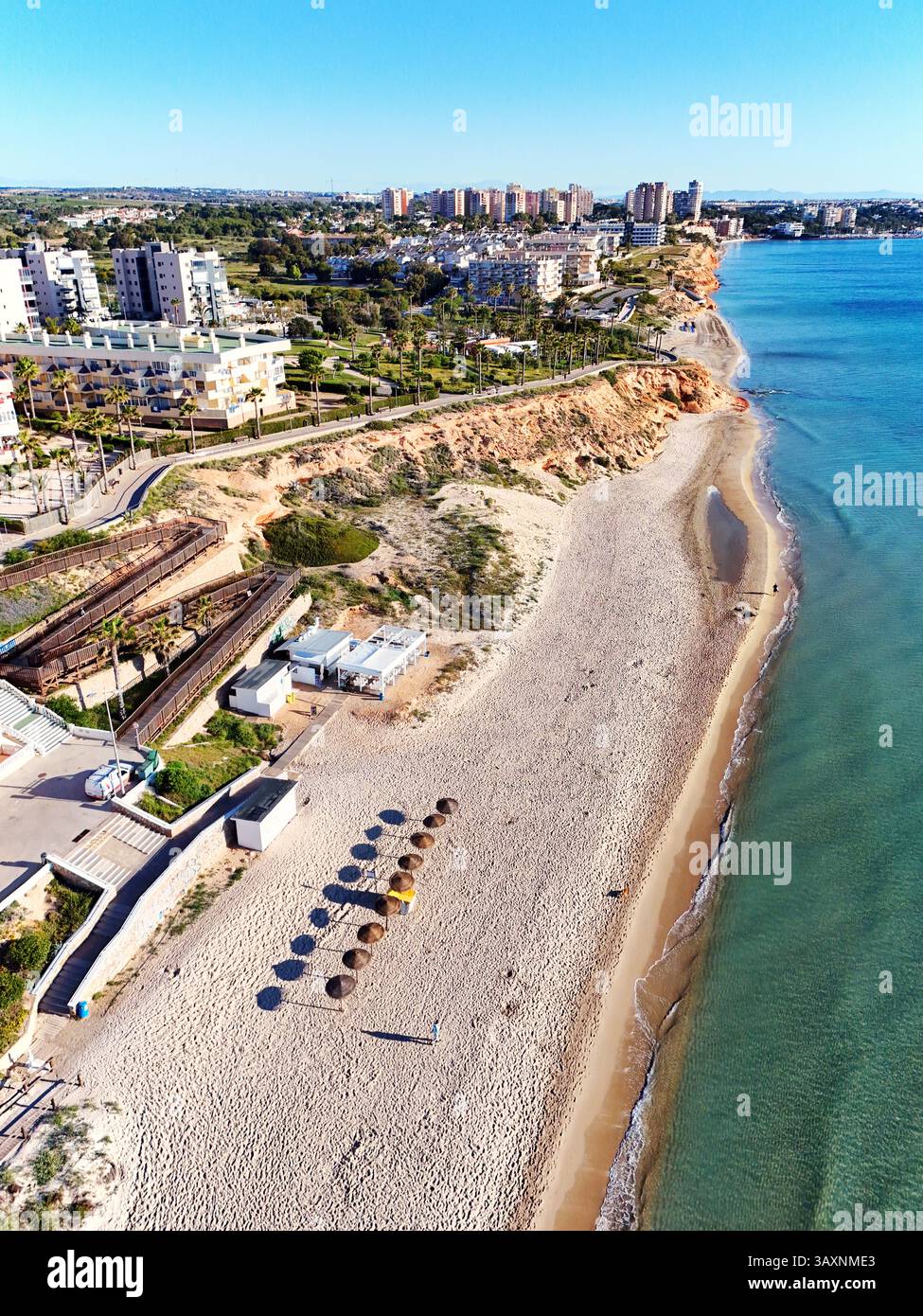Vue aérienne de la côte de Mil Palmeras, montrant les maisons en bord de mer, promenade, plage de sable et mer Méditerranée turquoise sous ciel bleu clair Banque D'Images