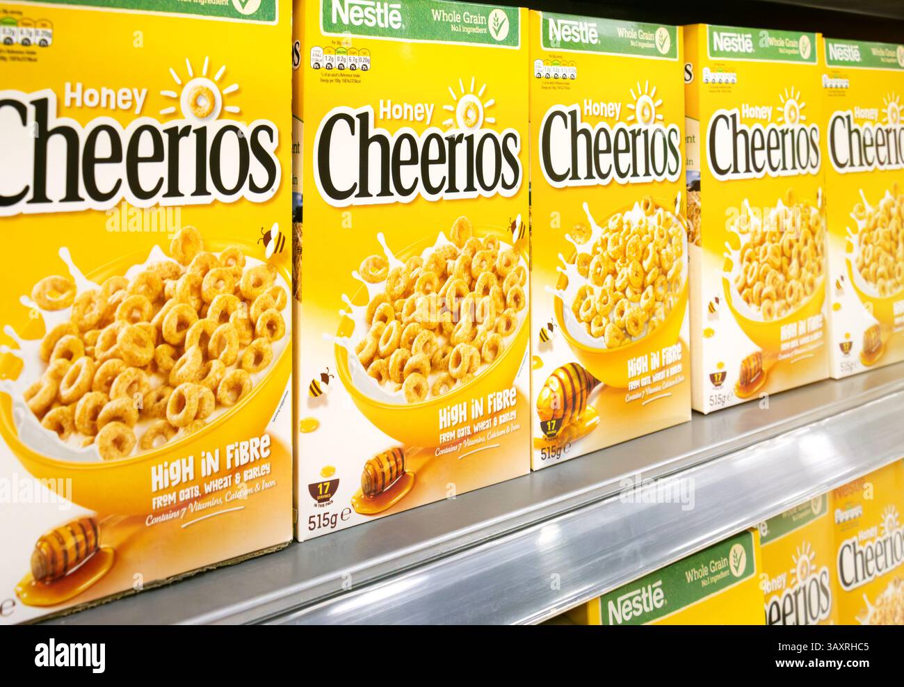 Boîtes de céréales Nestlé Honey Cheerios en stock sur l'étagère du magasin de détail. La marque emblématique de céréales pour petit-déjeuner à grains entiers mélangés enrichis est une marque classique. Banque D'Images