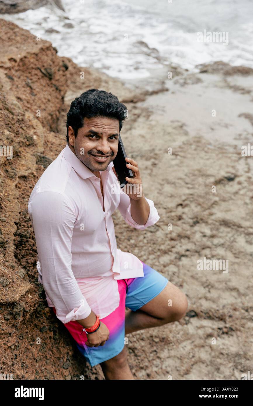 Un homme indien attirant et souriant a un appel téléphonique, photo d'en haut. Banque D'Images