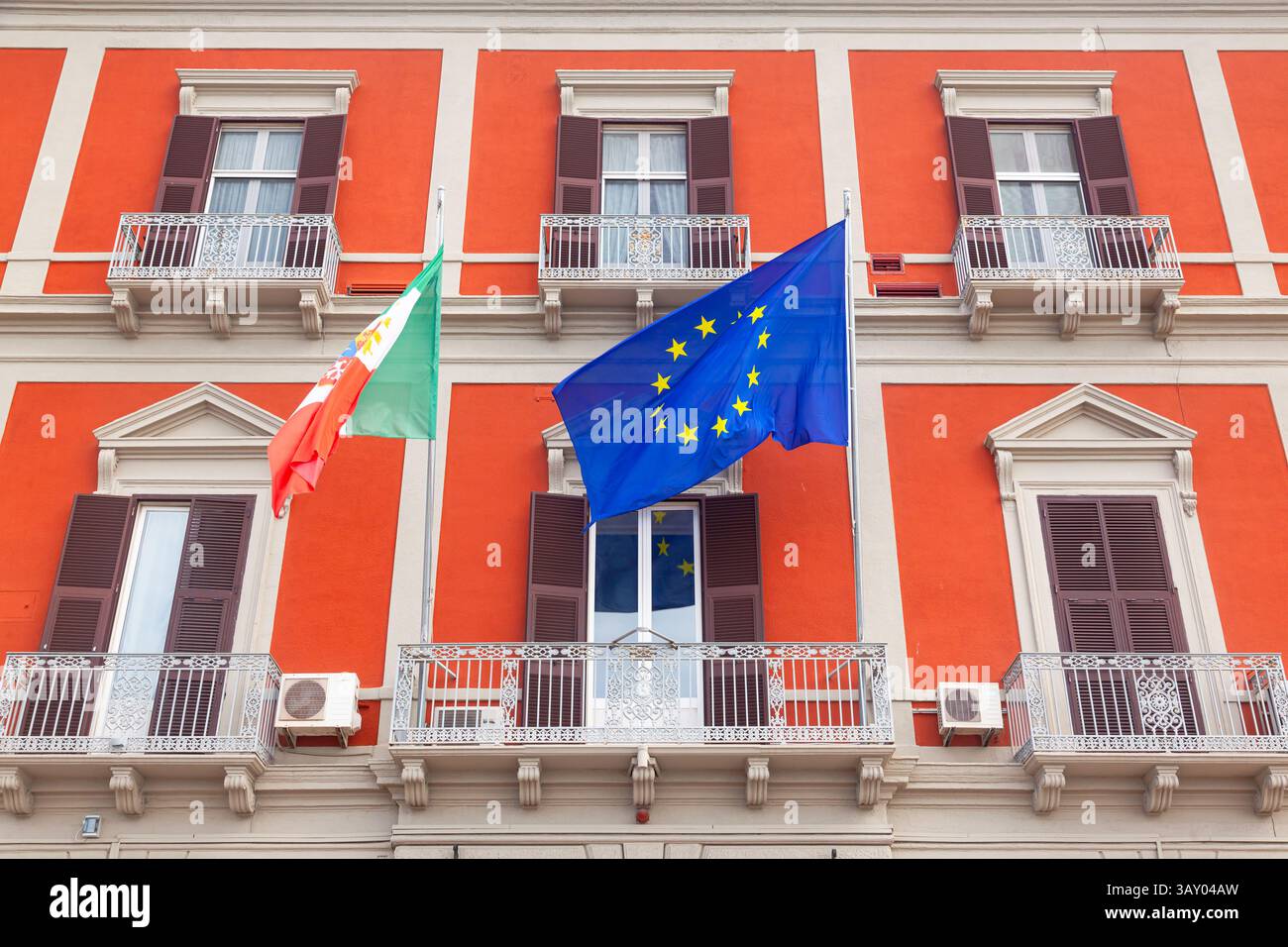 Façade d'un bâtiment classique avec le drapeau de l'Italie et de l'Union européenne au premier plan. Banque D'Images
