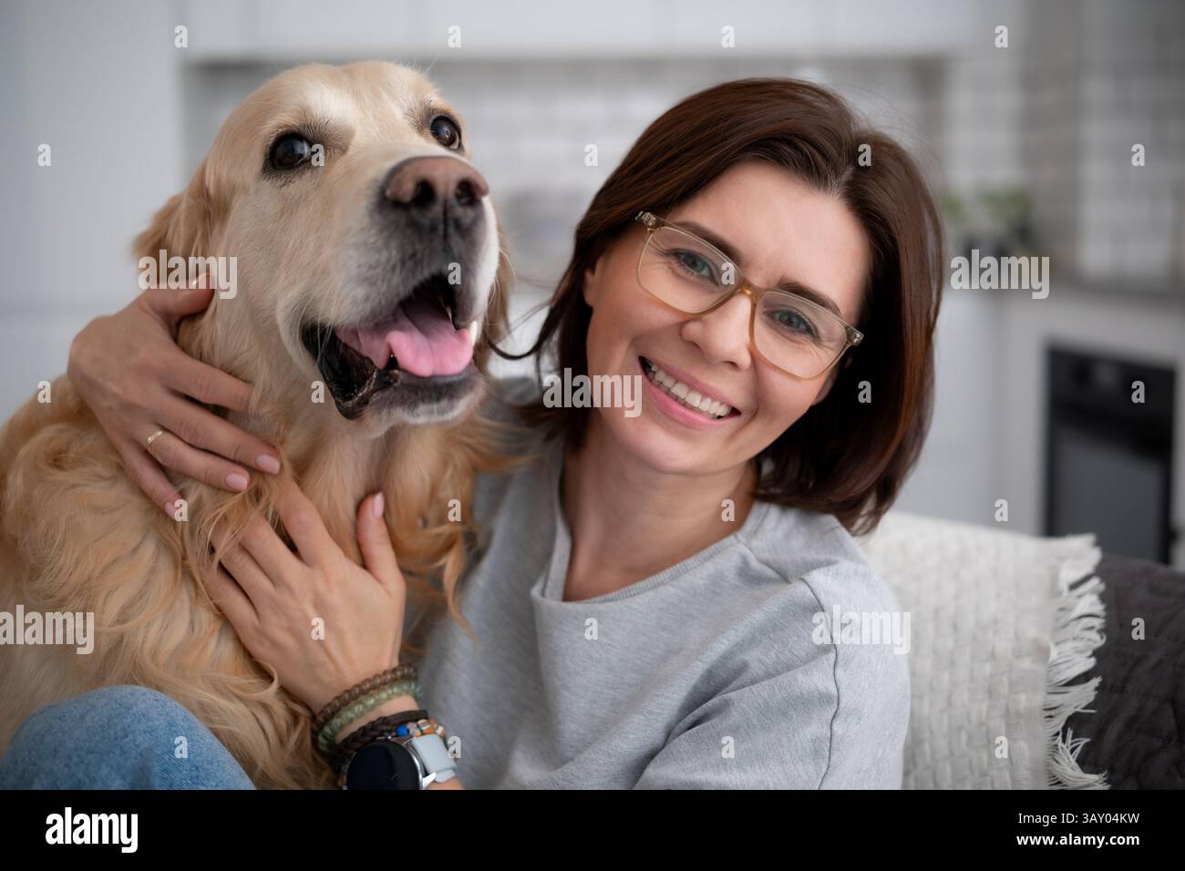 Joyeuse femme souriante embrasse adorable Golden Retriever à la maison Banque D'Images