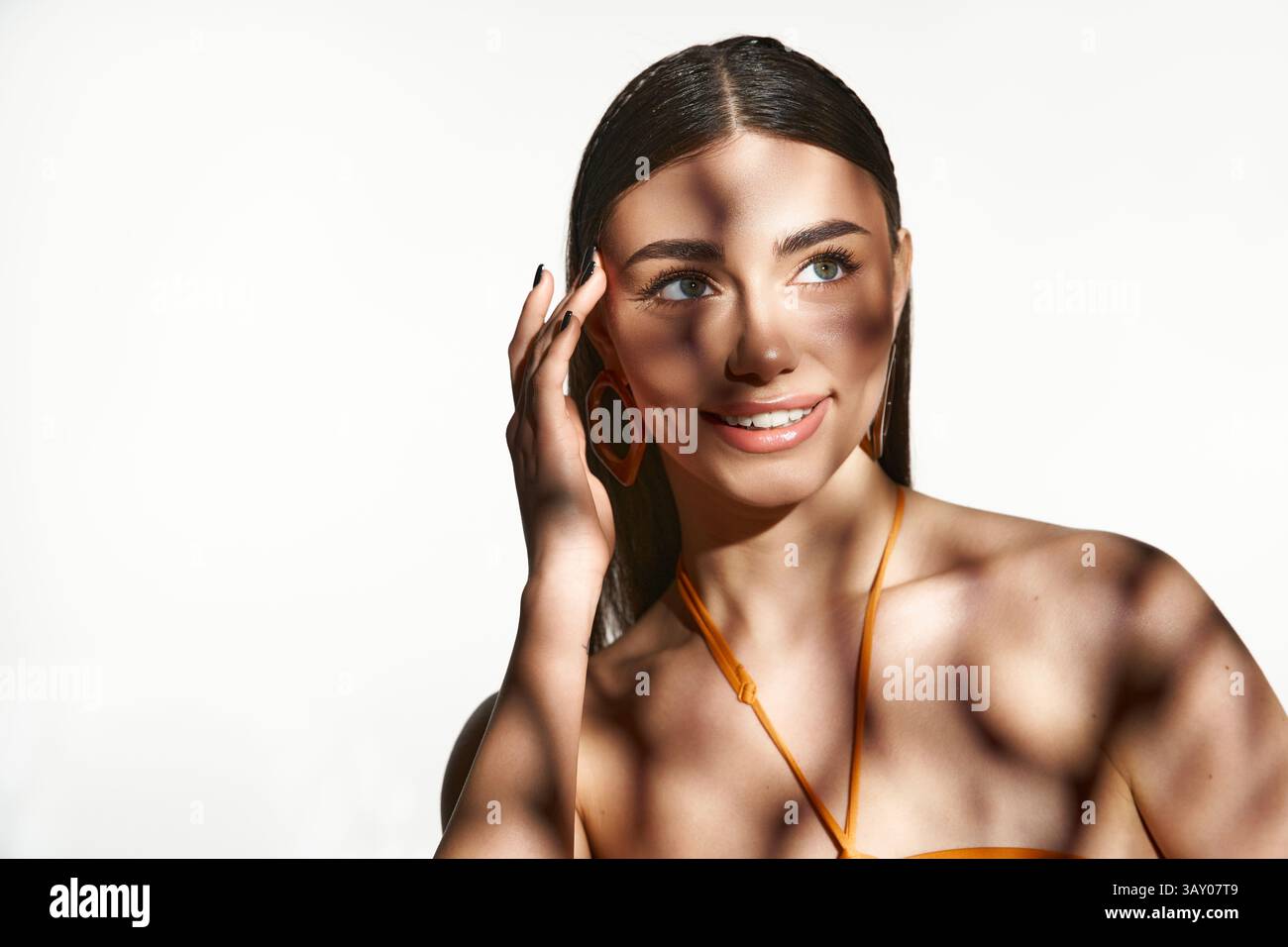 Une jeune femme embrasse l'été avec une lueur embrassée par le soleil et un sourire éclatant. Banque D'Images