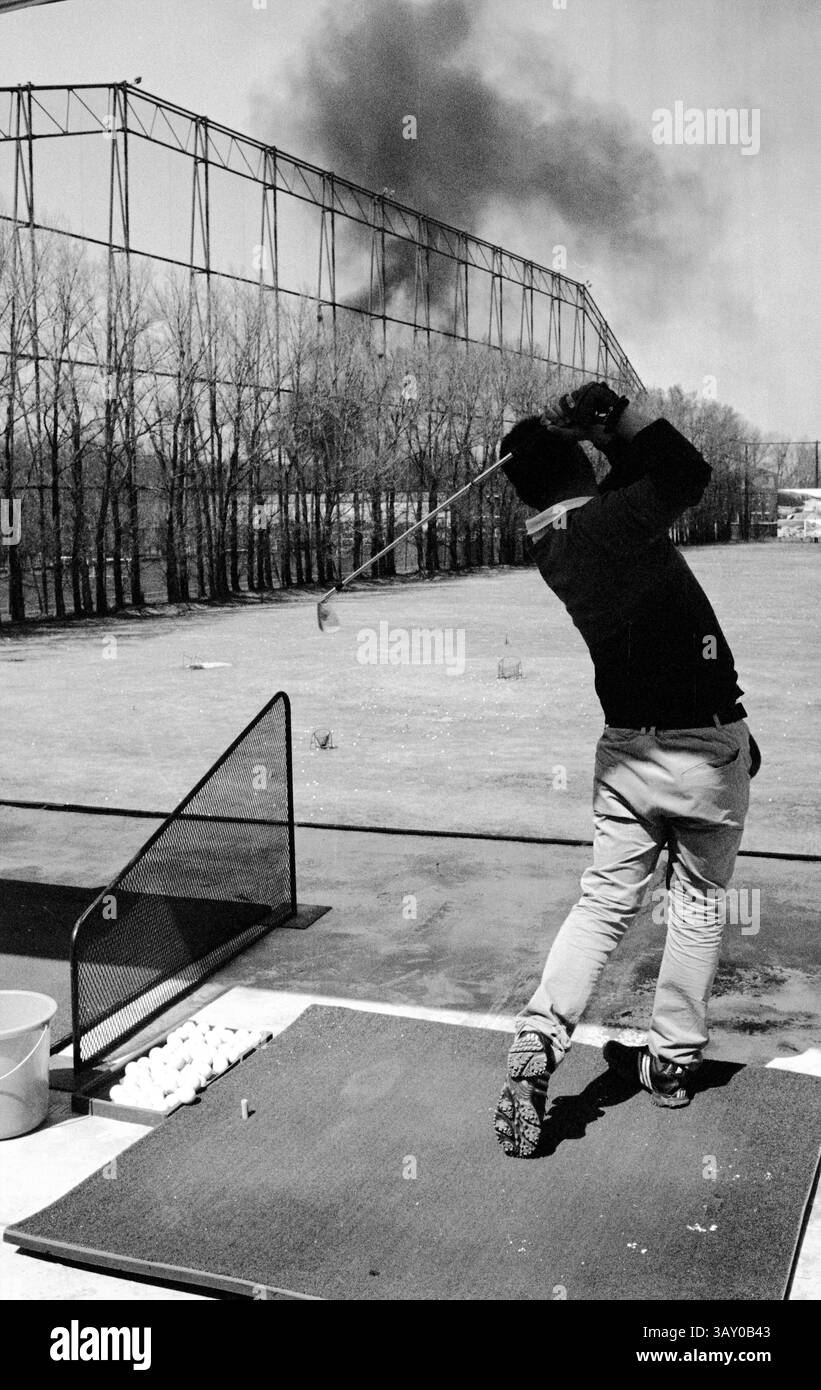 Les amateurs de golf pratiquent le swing à l'aire d'échauffement tandis que la fumée coule dans la distance par temps clair, 2011, Pékin, Chine Banque D'Images