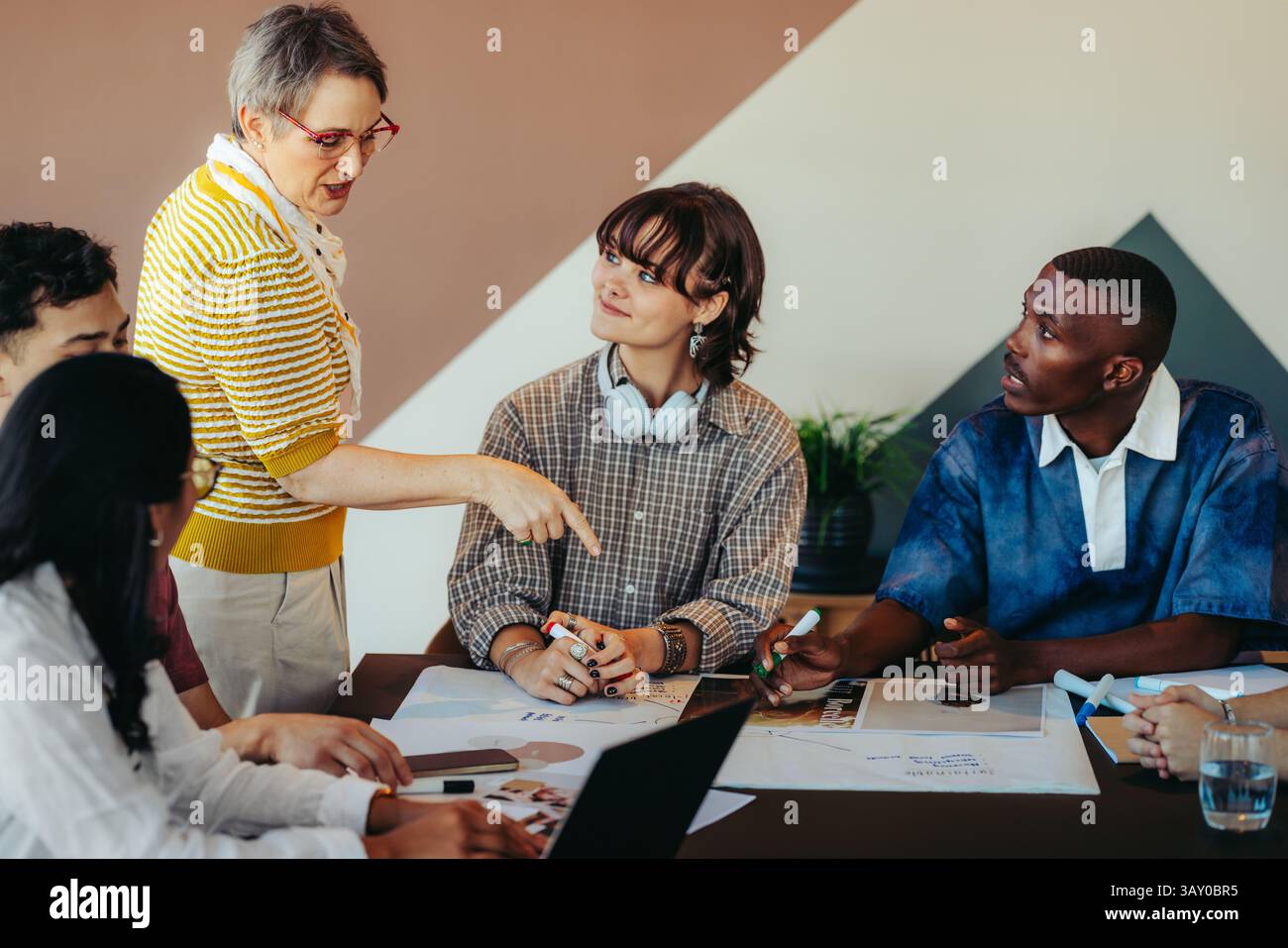 Une scène de classe moderne avec un groupe diversifié d'étudiants engagés dans la discussion, dirigé par un enseignant inspirant facilitant la collaboration et innovant Banque D'Images