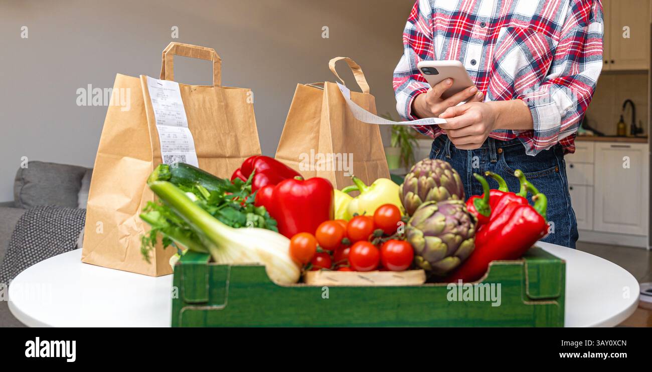 Service de livraison agricole de légumes frais biologiques. Personne féminine scannant le code QR sur la réception de la commande. Banque D'Images