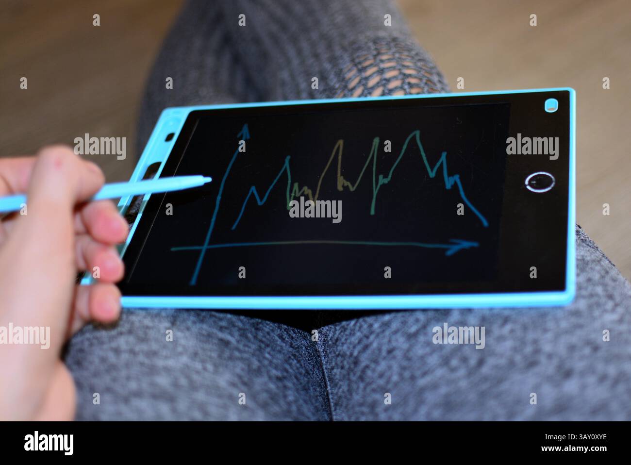 La femme tient une planche à dessin de jouets pour enfants sur ses genoux et dessine des graphiques au trait Banque D'Images