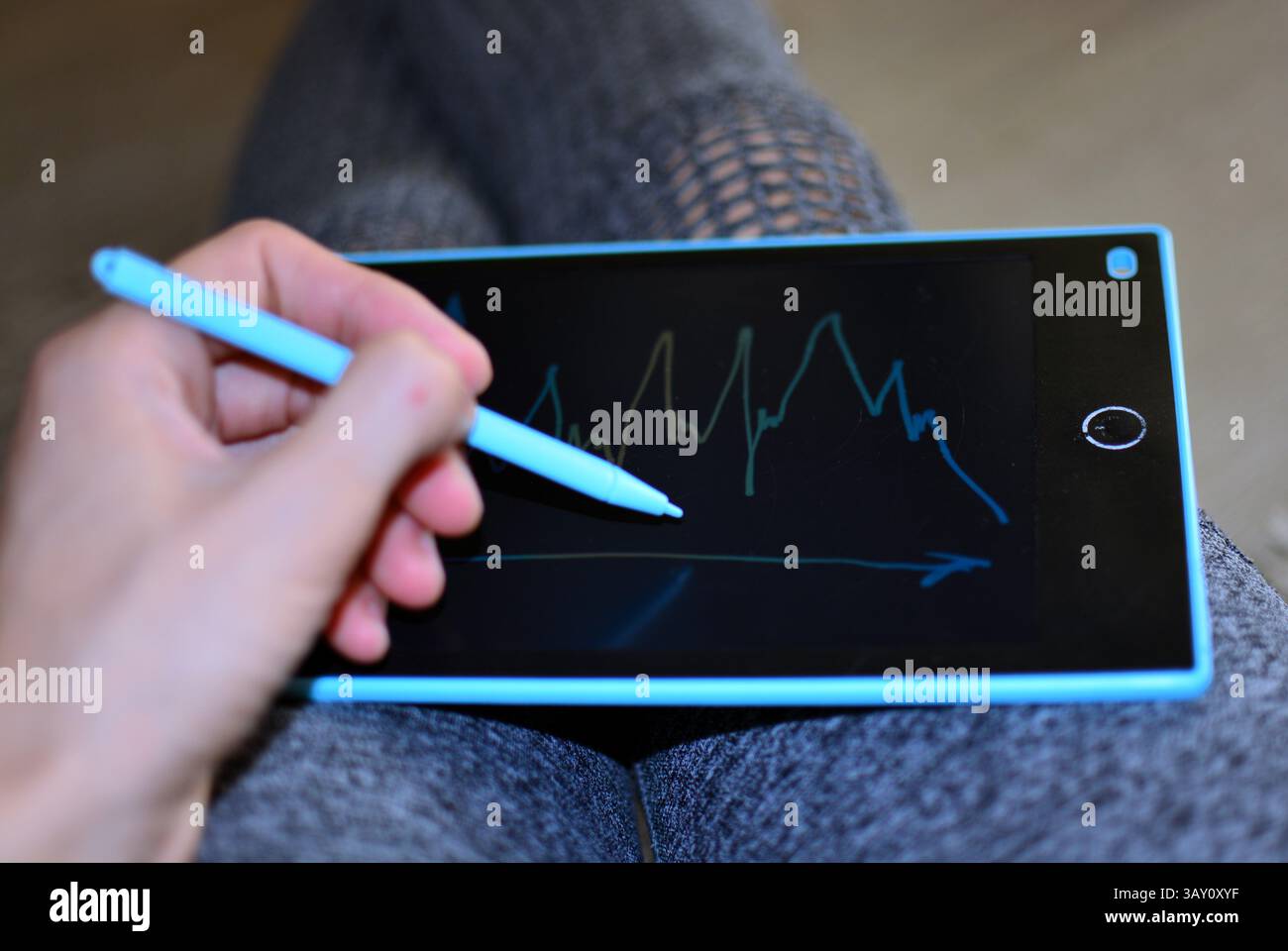 La femme tient une planche à dessin de jouets pour enfants sur ses genoux et dessine des graphiques au trait Banque D'Images