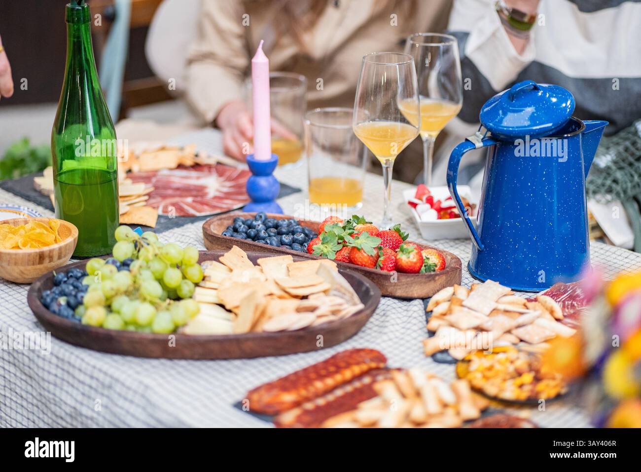 Une charcuterie vibrante composée de raisins, de fraises et de bleuets, accompagnée d'un assortiment de crackers et de boissons. Un rassemblement informel animé Banque D'Images