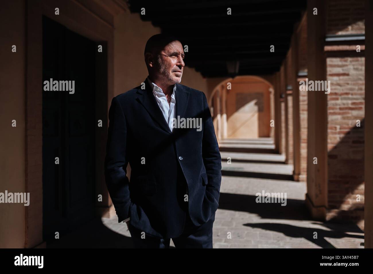 Un homme d'affaires confiant se tient dans un couloir ensoleillé, portant un costume. La scène transmet professionnalisme et détermination. Les ombres et la lumière créent Banque D'Images