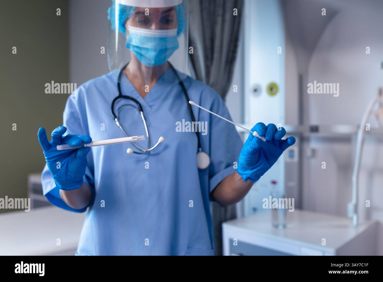 Infirmière de milieu adulte portant masque et écran facial manipulant des écouvillons nasopharyngés en salle d'essai clinique Banque D'Images