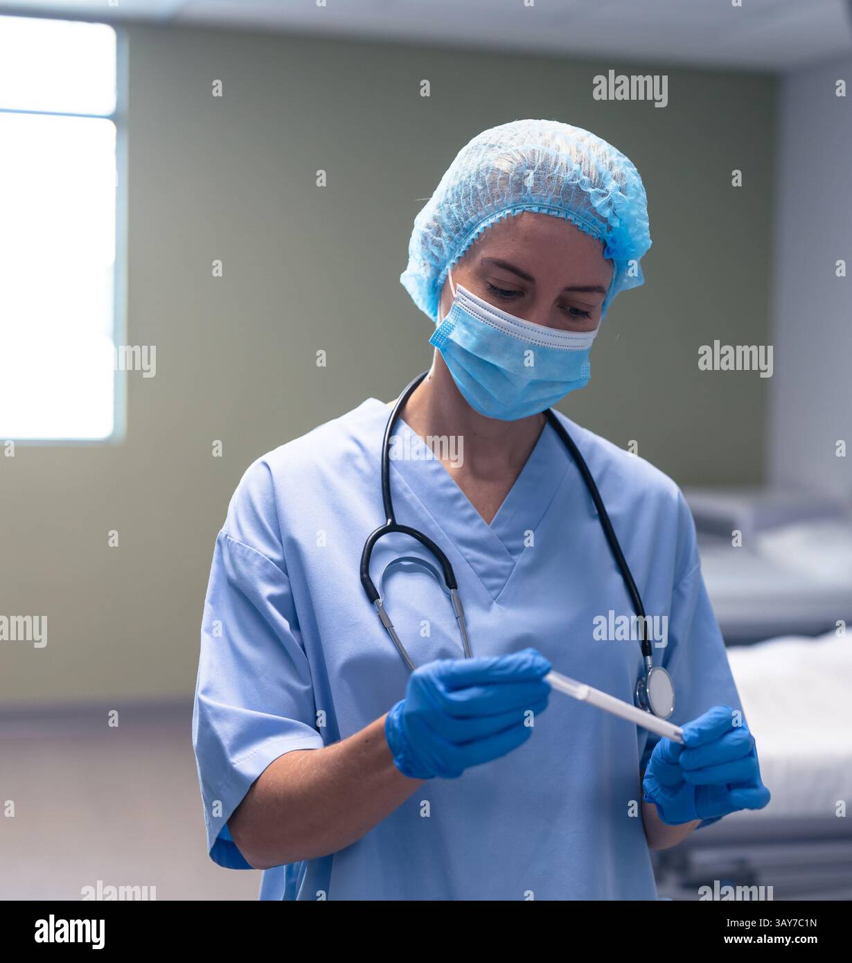 Jeune adulte femme professionnelle médicale debout dans la salle d'examen clinique, avec écouvillon dans un tube transparent Banque D'Images