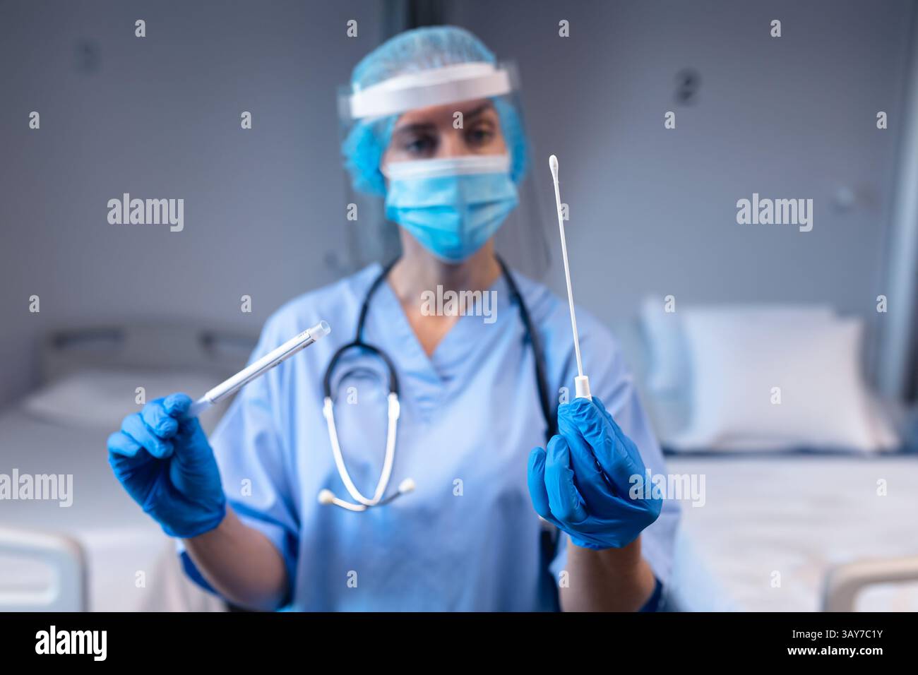 Travailleuse de santé tenant un écouvillon stérile, tube d'échantillonnage dans un laboratoire d'hôpital avec stéthoscope Banque D'Images