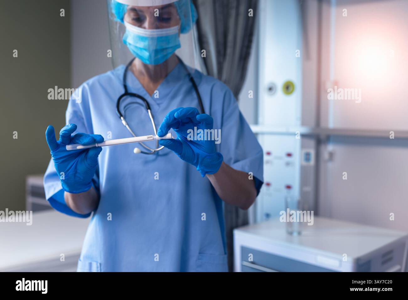 Infirmière portant un masque et des gants tenant l'écouvillon médical dans la salle d'examen clinique, avec stéthoscope Banque D'Images