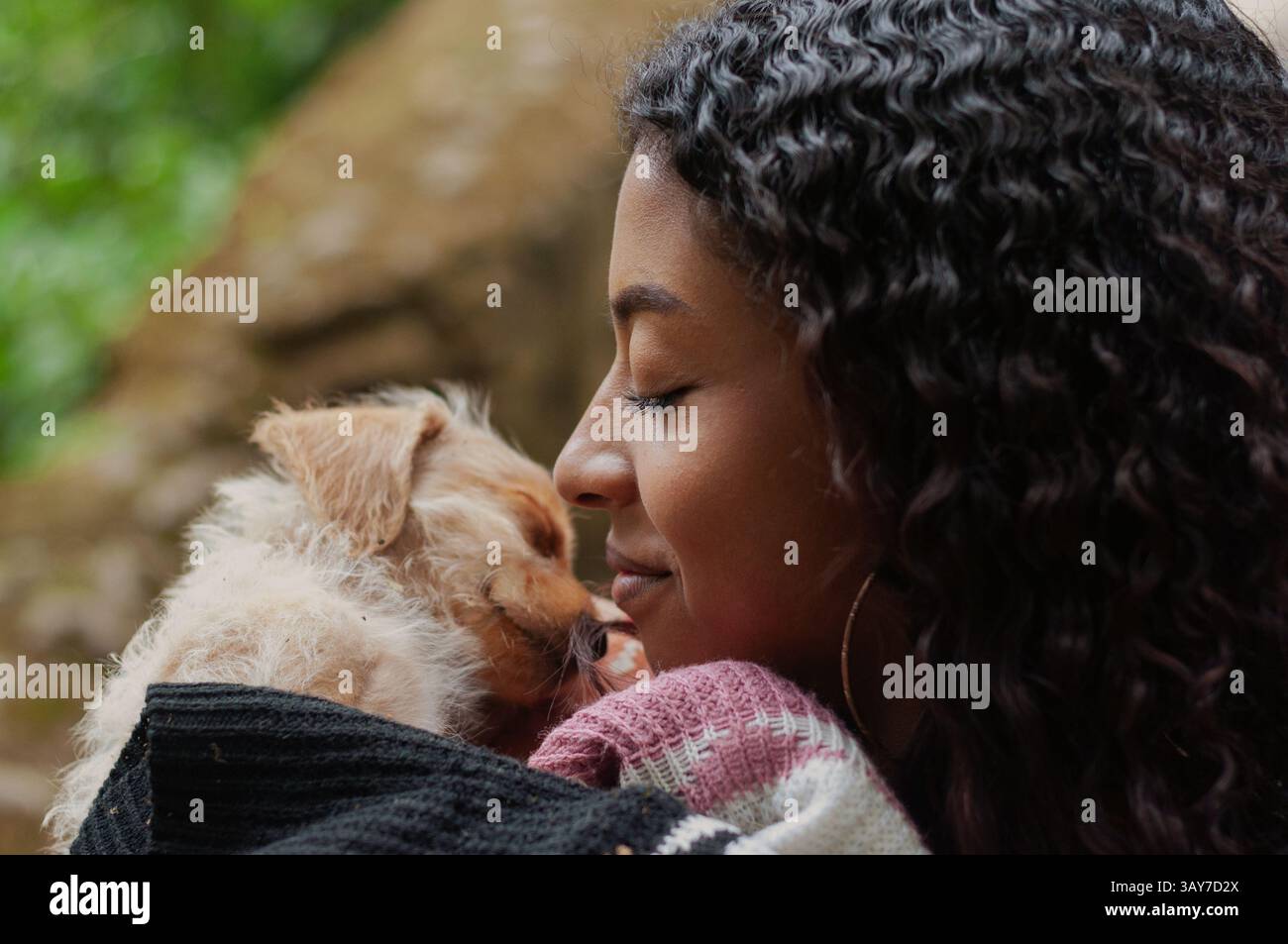 Une femme joyeuse partage un moment d’amour avec son petit chien dans un cadre extérieur serein, entouré par la nature Banque D'Images