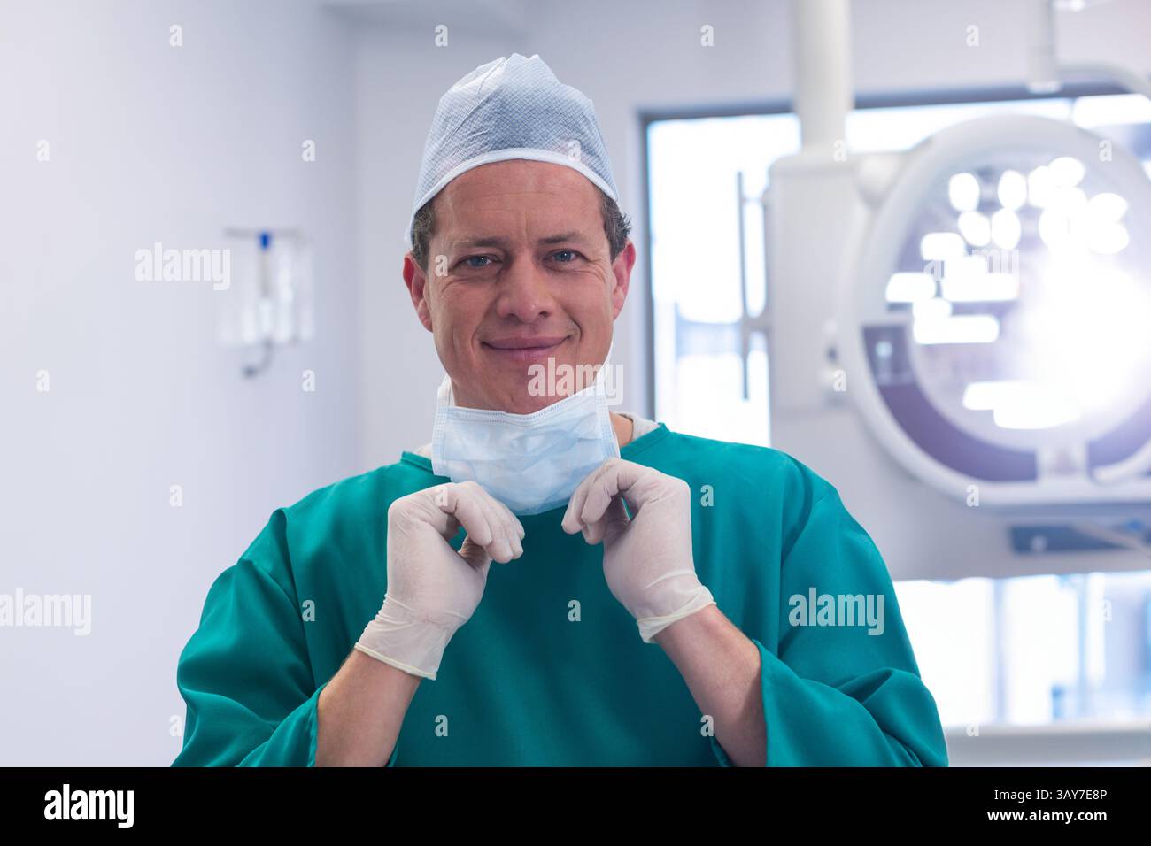 Chirurgien ajustant le masque chirurgical dans la salle d'opération, avec plafonnier et gants Banque D'Images