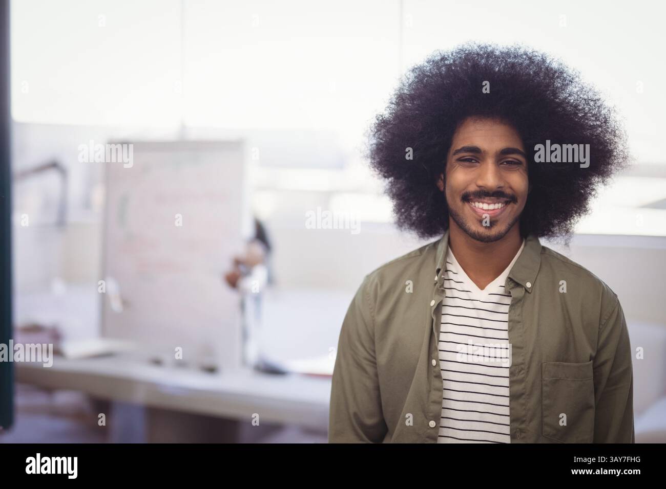 Homme indien souriant à la caméra dans le bureau, avec des griffonnages de tableau blanc des papiers éparpillés, espace de copie Banque D'Images