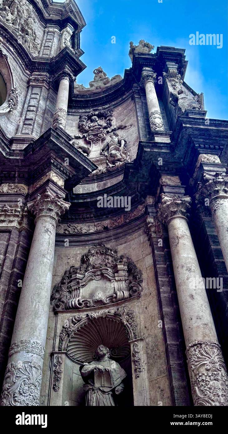 Façade d'église baroque à Valence avec des sculptures en pierre ornées, des colonnes et une statue religieuse sous un ciel bleu clair. - Image de stock capturée avec un smartphone