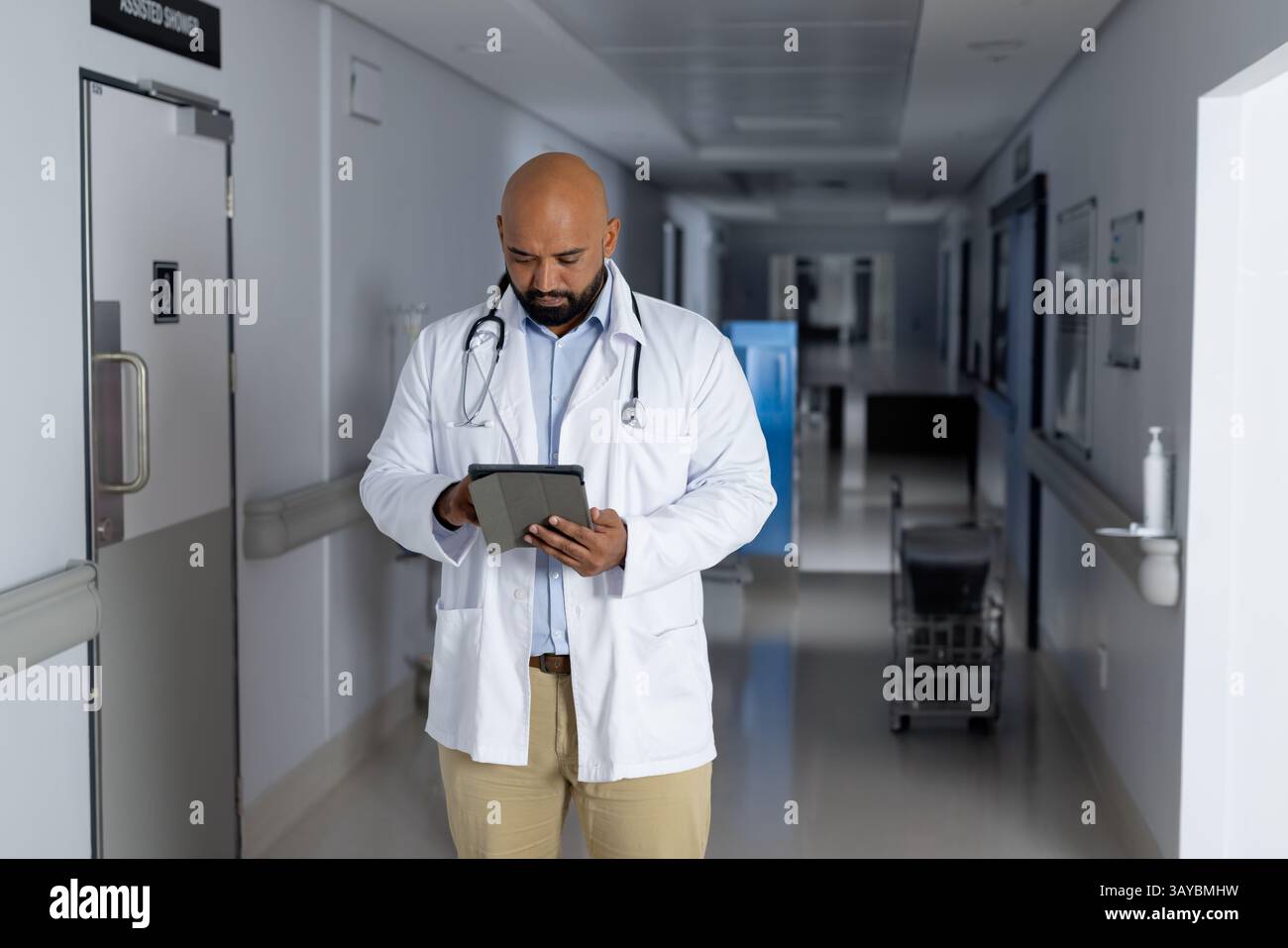 Médecin masculin examinant comprimé dans le couloir de l'hôpital, avec stéthoscope et brancard en vue Banque D'Images