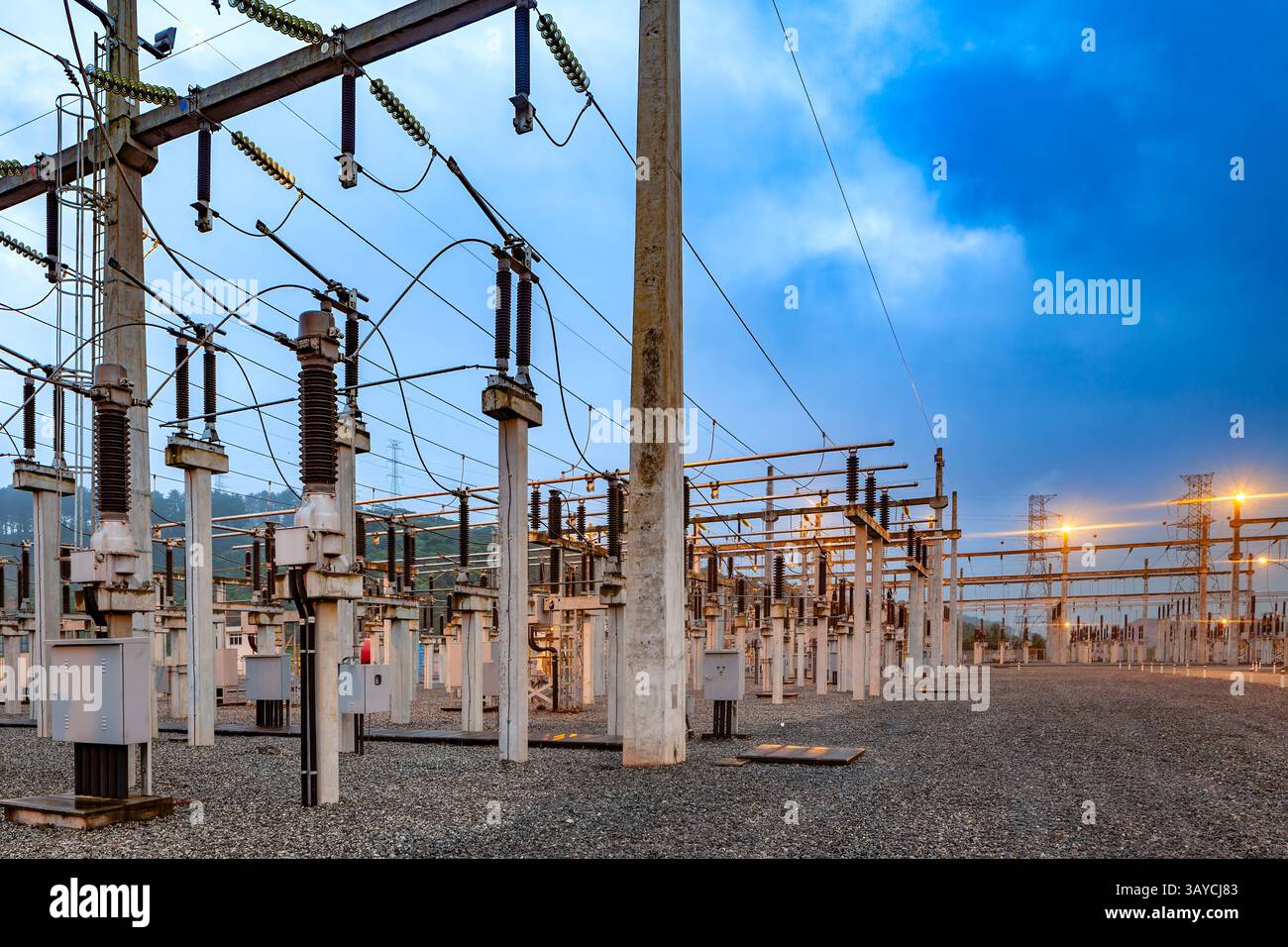 Sous-station électrique au Brésil, éclairée au crépuscule, avec son réseau de tours, transformateurs et lignes électriques contre la lumière du ciel. Banque D'Images