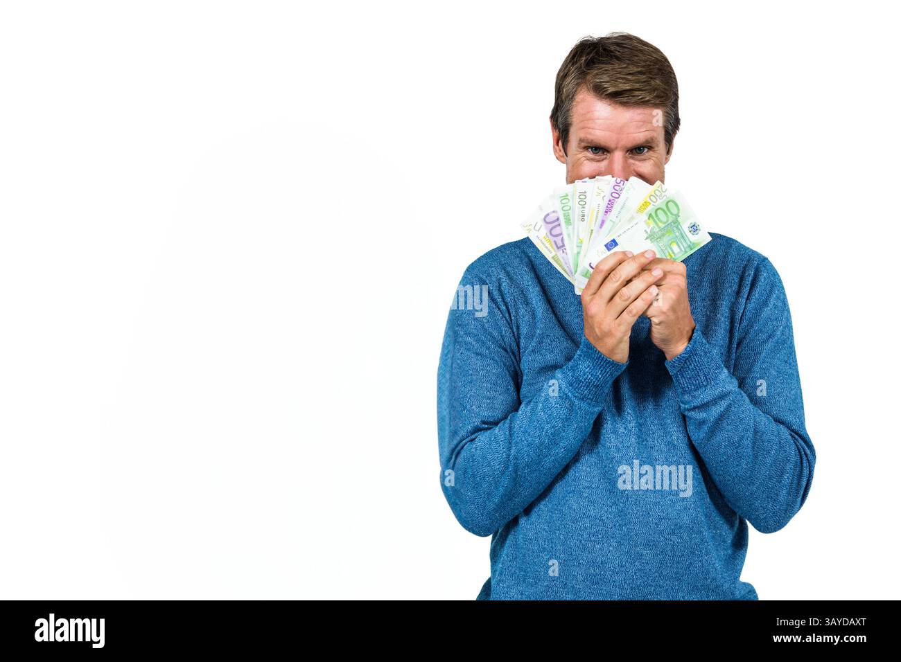 Homme tenant des billets en euros sur le visage en studio, montrant une expression ludique, espace de copie Banque D'Images