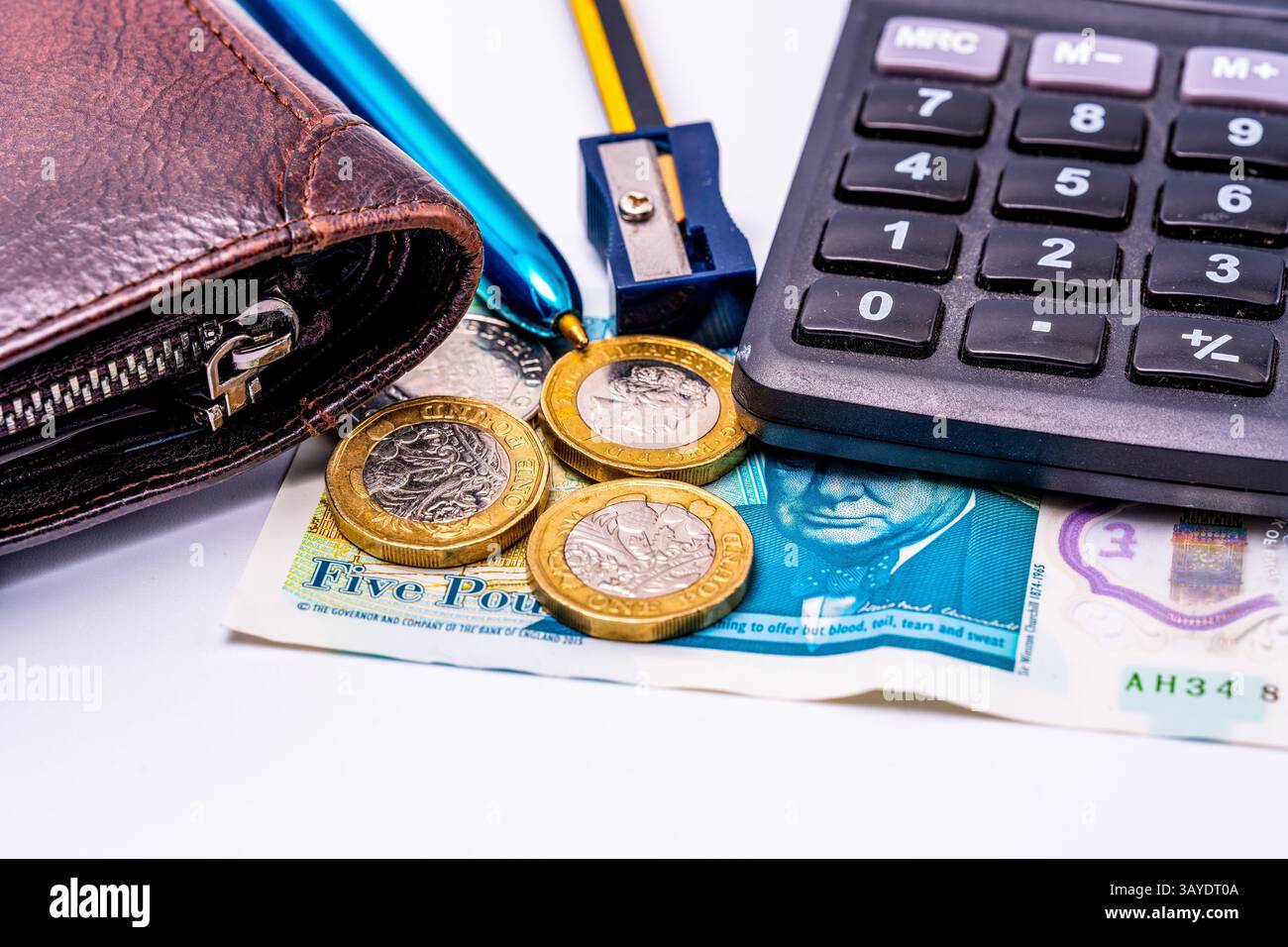 Plan macro d'outils financiers britanniques, avec portefeuille en cuir, pièces en livres sterling, billet de cinq livres, touches de calcul, stylo métallique et taille-crayon bleu Banque D'Images