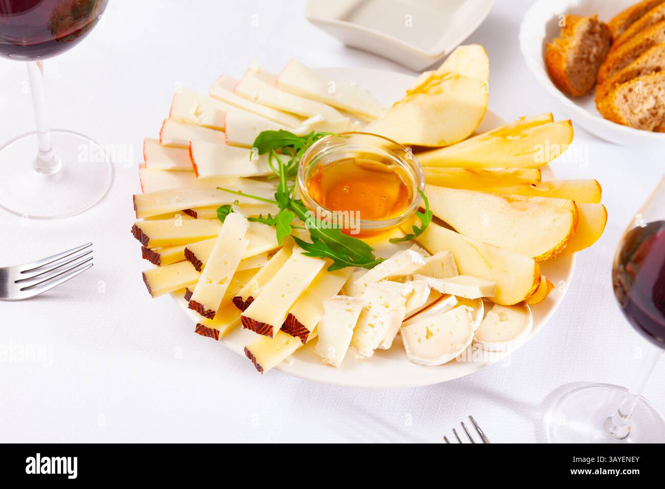 Assiette avec différents types de fromage et une tasse de miel Banque D'Images