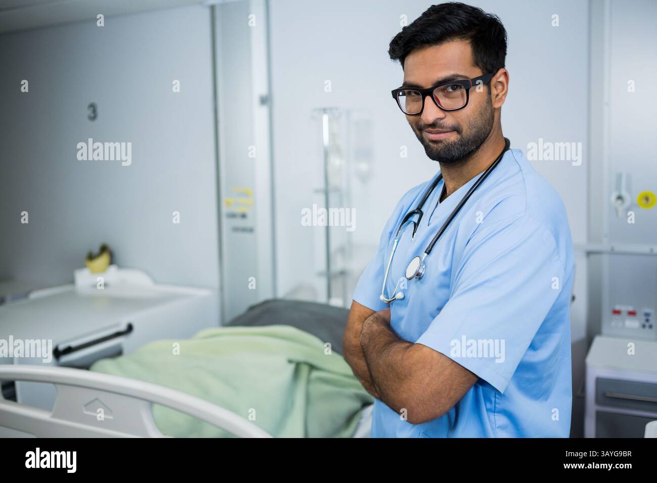Médecin masculin asiatique debout avec les bras croisés dans la chambre d'hôpital, stéthoscope, statif IV, espace de copie Banque D'Images
