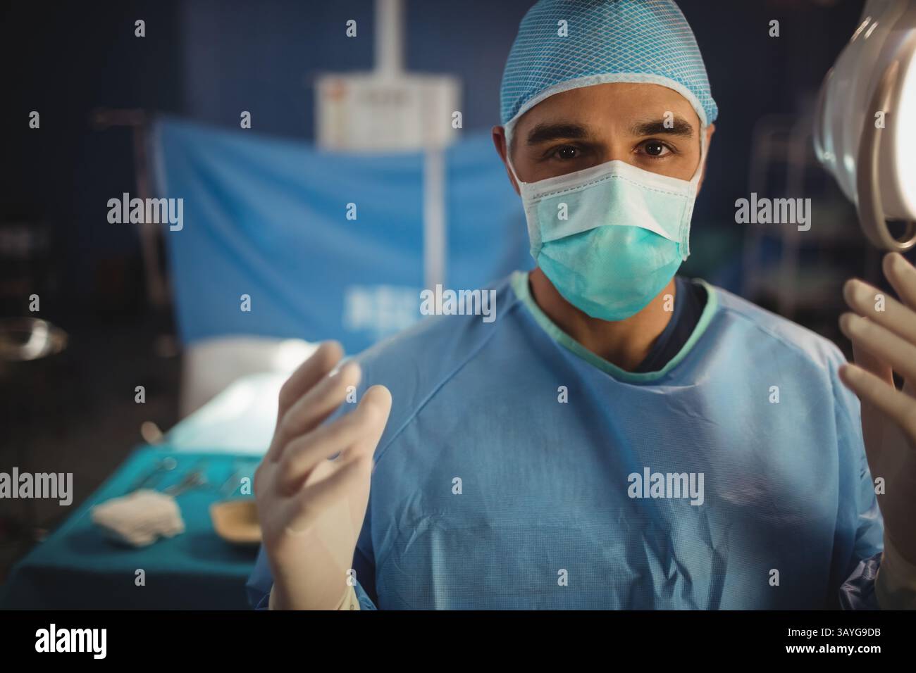 Chirurgien debout dans la salle d'opération portant un masque de bonnet chirurgical et des gants, préparant les instruments Banque D'Images