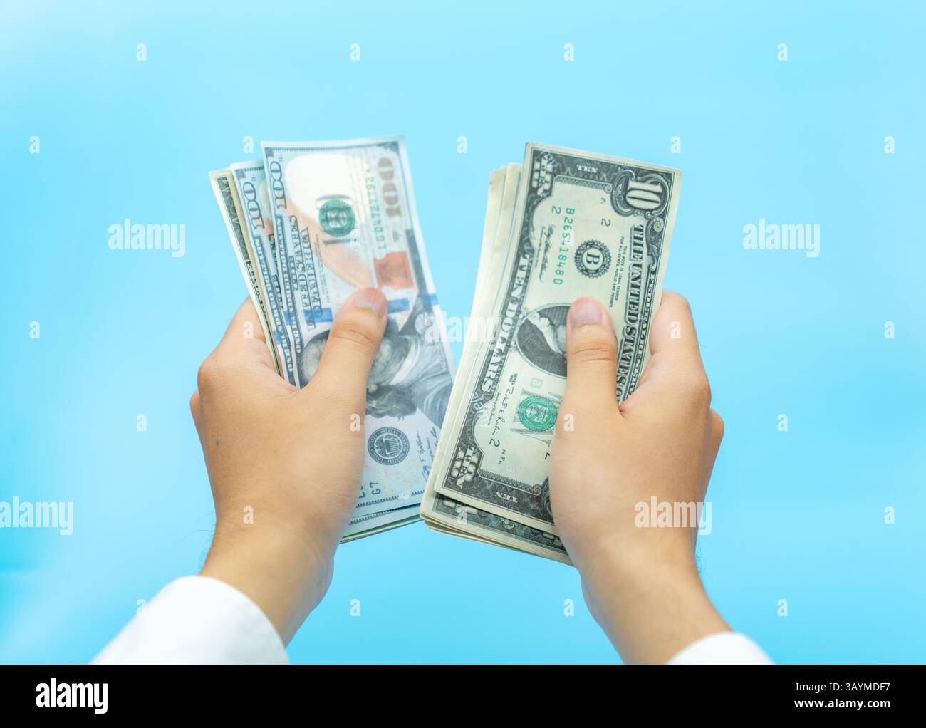 Main d'homme en chemise blanche comptant des billets de banque en dollars sur fond bleu aqua. Banque D'Images