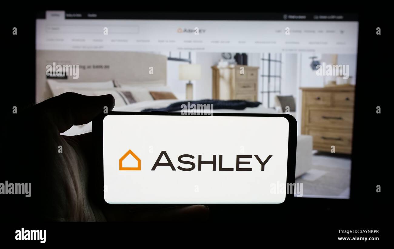 Allemagne. 17 avril 2025. Dans cette illustration photo, une personne tient un téléphone portable avec le logo de la société américaine Ashley Furniture Industries Inc sur l'écran devant la page Web. Crédit : SOPA images Limited/Alamy Live News Banque D'Images