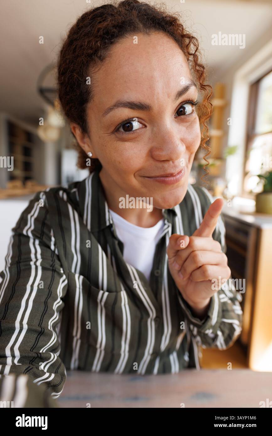 Femme dans ses années 30 pointant l'index vers la caméra dans un cadre de cuisine moderne avec lumière naturelle Banque D'Images