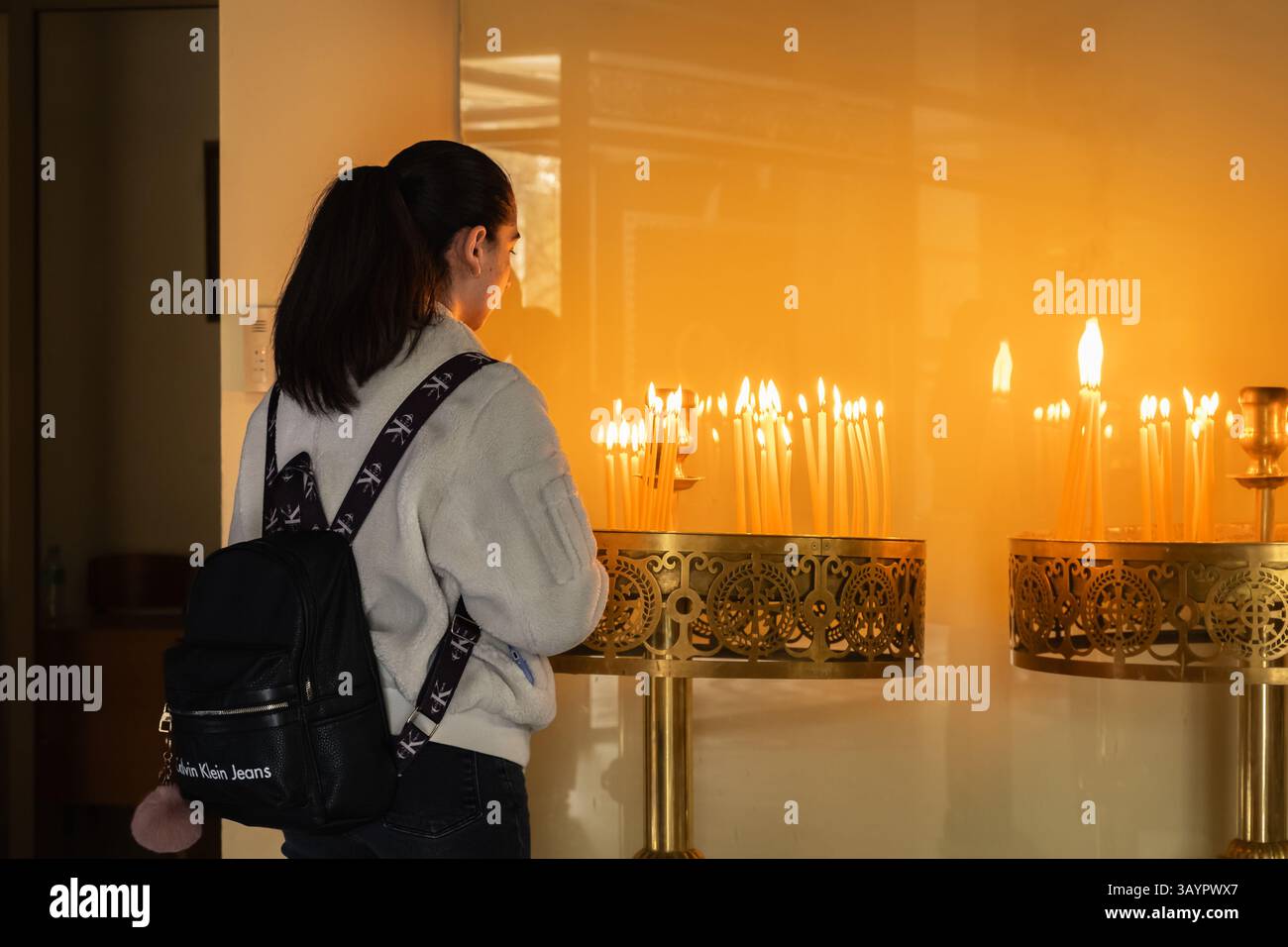 Jeune femme priant dans l'église près de bougies allumées.. Femme debout à côté des bougies allumées. Christianisme, foi et croyance concept. Résurrection de Chr Banque D'Images