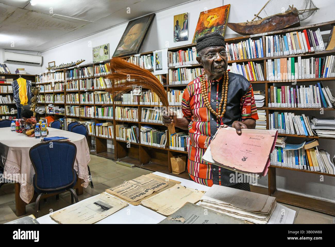 Douala, Cameroun. 17 mars 2025. Alexandre Kum'a Ndumbe Ill, prince camerounais, historien et professeur émérite dans plusieurs universités, présente des documents d'archives sur l'histoire du Cameroun à sa bibliothèque de Douala, Cameroun, le 17 mars 2025. POUR ALLER AVEC 'Feature : prince camerounais brandit la plume comme épée pour la renaissance africaine' crédit : Kepseu/Xinhua/Alamy Live News Banque D'Images