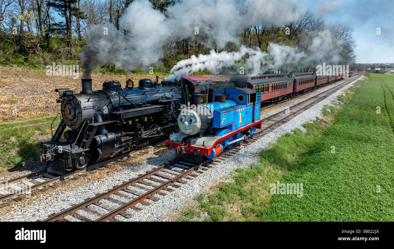 Ronks, Pennsylvanie, le 17 avril 2025 - deux trains à vapeur, l'un d'entre eux, Thomas the Tank Engine, voyagent côte à côte le long d'un chemin de fer pittoresque dans un cadre rural Banque D'Images