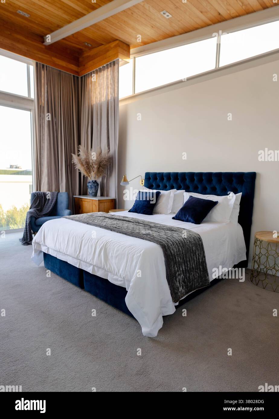 Lit king-size installé dans une chambre moderne, avec tête de lit marine, draps blancs et herbe de pampa Banque D'Images Lit king-size installé dans une chambre moderne, avec tête de lit marine, draps blancs et herbe de pampa Banque D'Images