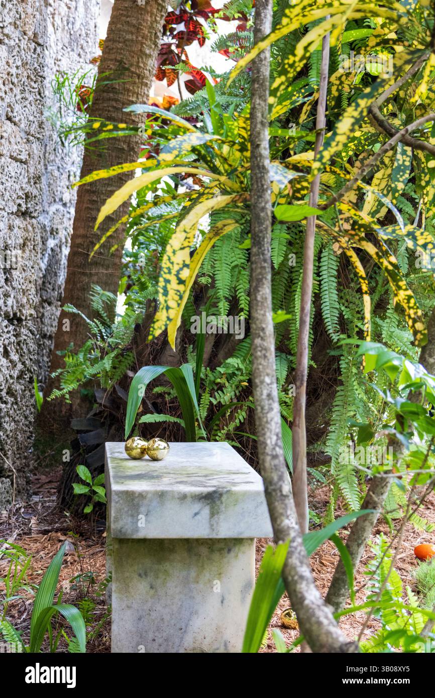 Deux œufs de Pâques dorés nichés ensemble sur un banc de pierre dans un coin confortable, situé dans un jardin tropical. Banque D'Images