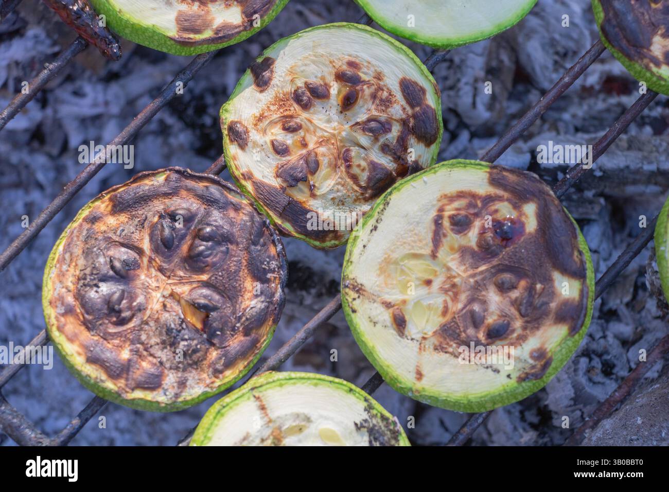 Tranches de courgettes grillées sur le gril, gros plan des parties carbonisées de légumes tranchés. Banque D'Images