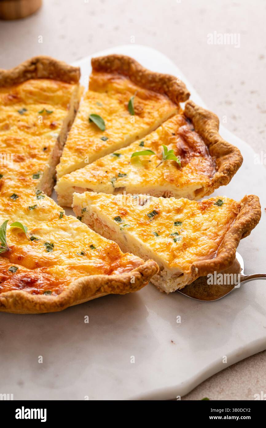 Quiche de saumon fraîchement cuite sur une planche de service, idée de petit déjeuner sain Banque D'Images