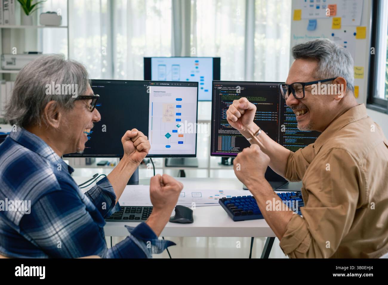 L'équipe de développeurs senior célèbre le succès de la collaboration logicielle et du codage sur un poste de travail informatique moderne Banque D'Images