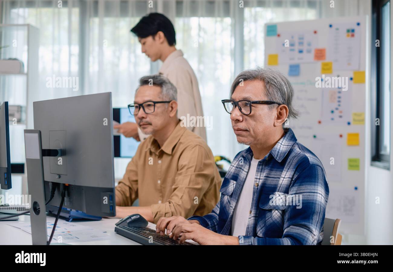 Groupe de senior asiatique dans un développement logiciel collaboratif analysant des organigrammes lors d'une formation bootcamp Banque D'Images