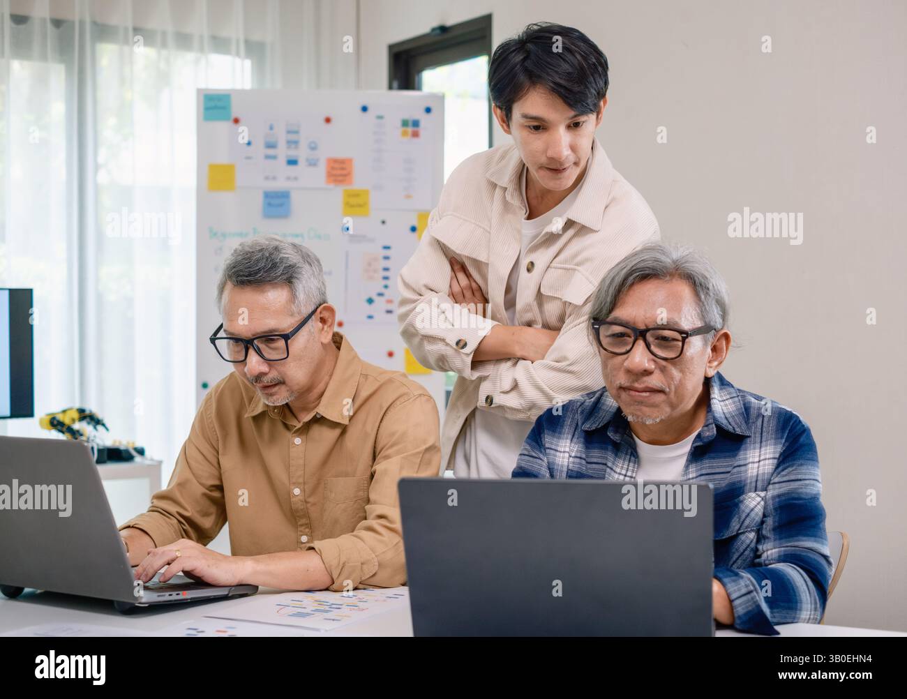 Groupe de senior asiatique dans un développement logiciel collaboratif analysant des organigrammes lors d'une formation bootcamp Banque D'Images