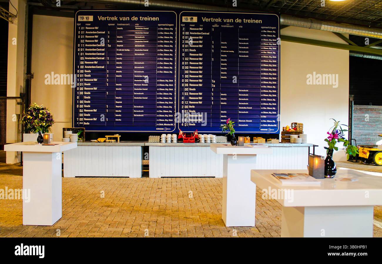 Configuration d'événement intérieur avec tables et grand panneau de départ de train. Banque D'Images