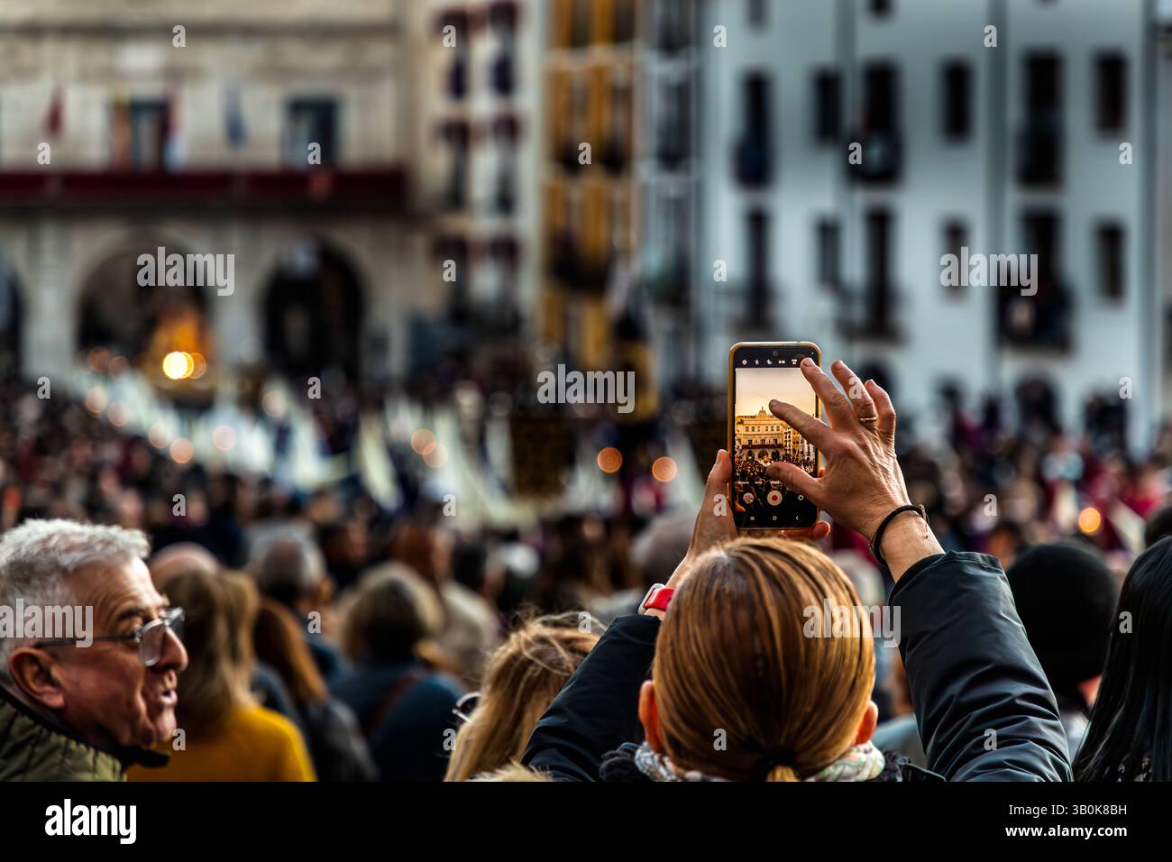 Une personne photographie une procession à Cuenca avec son smartphone. Beaucoup de gens regardent l'événement. Calle San Pedro, Cuenca, Castille-la Manche, Espagne Banque D'Images