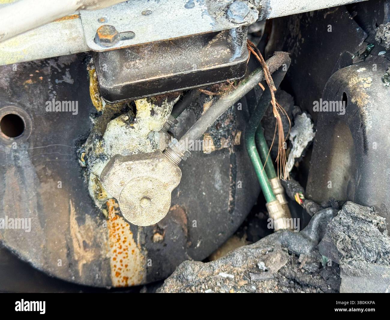 Soupape de compresseur de climatisation brûlée d'une voiture montrant des dommages causés par la chaleur, du matériau d'étanchéité fondu, du câblage en cuivre exposé et du lin réfrigérant connecté Banque D'Images