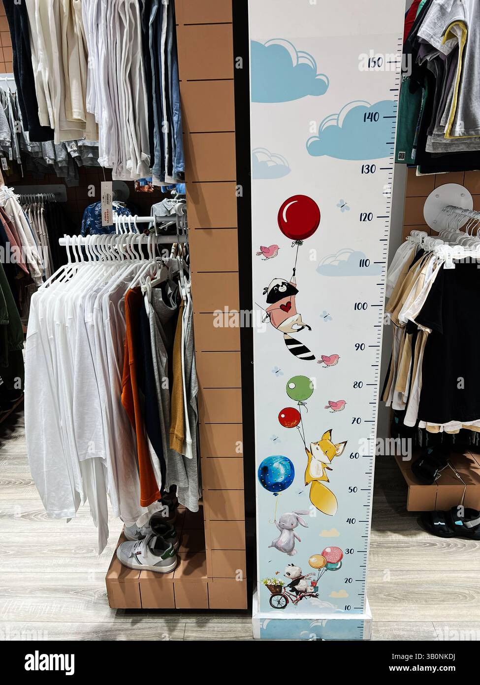 Kiev, Ukraine - 23 avril 2025 : tableau coloré de la hauteur des animaux dans un charmant cadre de vente au détail avec des vêtements pour enfants. Banque D'Images