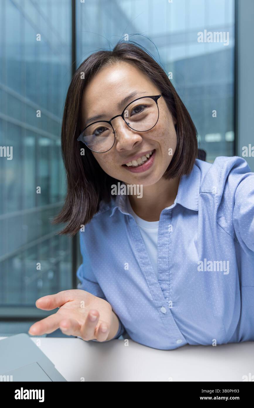 Jeune femme d'affaires utilisant l'application téléphonique pour l'appel vidéo, vue de la caméra de smartphone. Employé de bureau regardant la caméra souriant et parlant à des collègues et partenaires assis à leur bureau dans le bureau. Banque D'Images