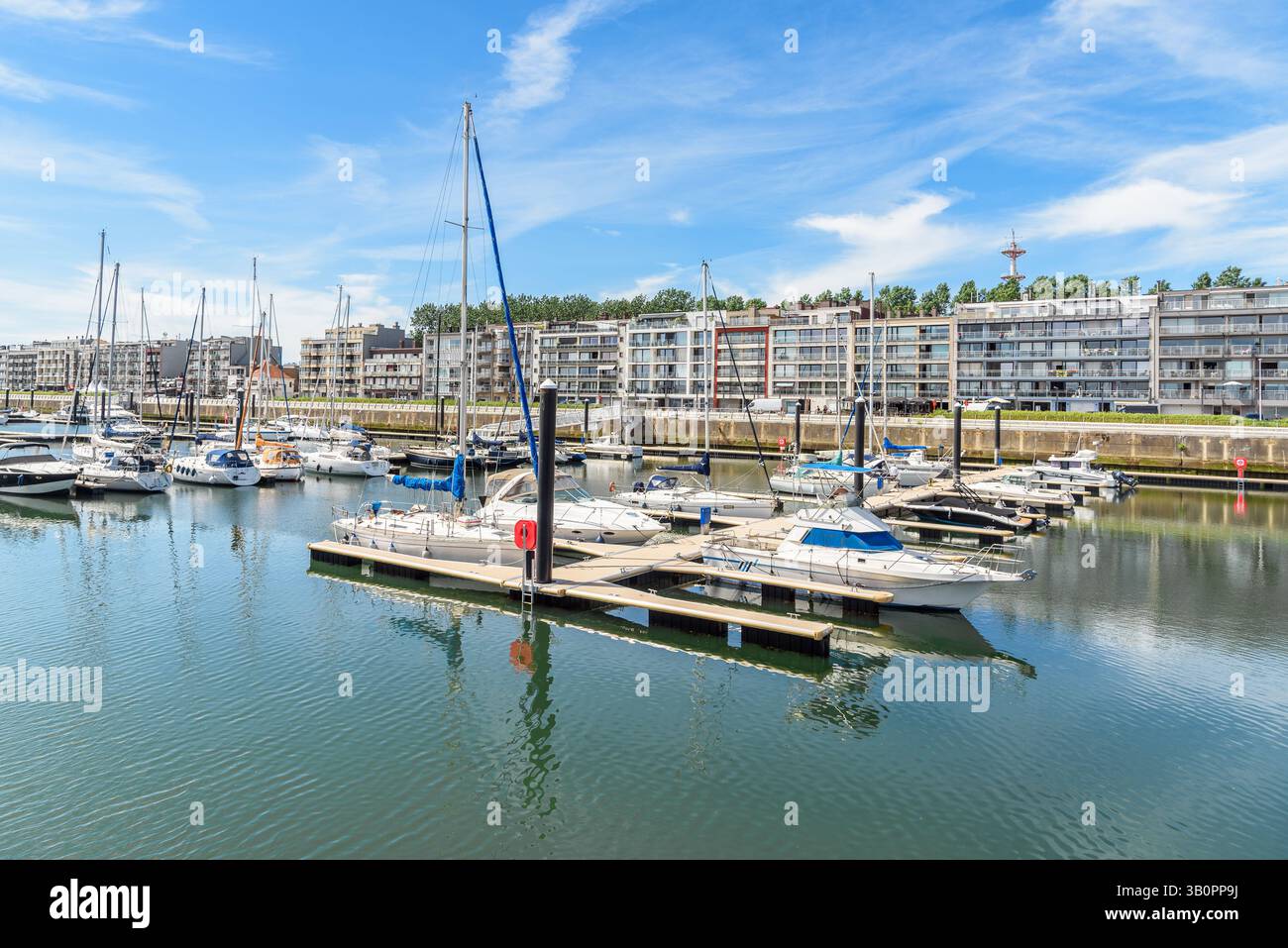 Yachts dans une marina bordée d'immeubles d'appartements modernes par une journée d'été ensoleillée Banque D'Images