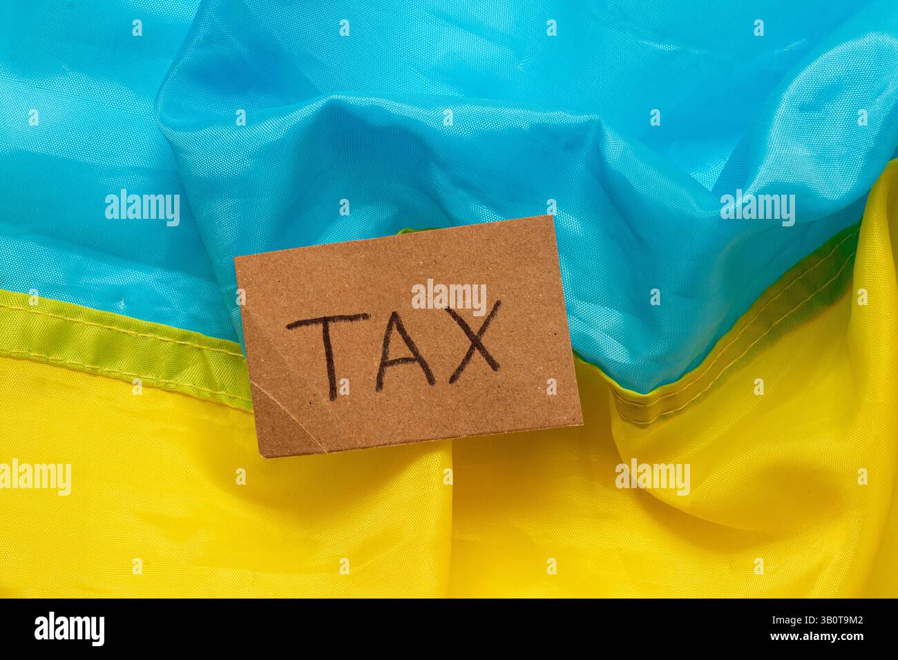 L'inscription taxe sur un morceau de carton sur le fond du drapeau bleu et jaune de l'Ukraine, le concept des taxes en Ukraine, l'économie Banque D'Images