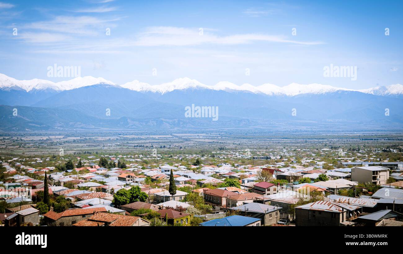 Vue panoramique de Telavi, une ville de l'est de la Géorgie, avec des toits au premier plan et des montagnes du Caucase enneigées au loin sous un clair Banque D'Images
