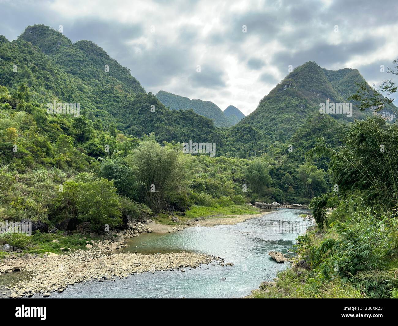 Rver serpente à travers des montagnes verdoyantes sous un ciel nuageux, mettant en valeur la beauté naturelle et la tranquillité à Guangxi, en Chine. Banque D'Images Rver serpente à travers des montagnes verdoyantes sous un ciel nuageux, mettant en valeur la beauté naturelle et la tranquillité à Guangxi, en Chine. Banque D'Images